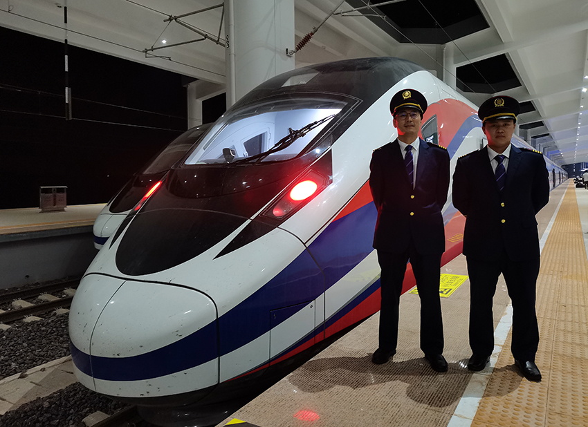 劉銀能（右一）與中國(guó)師父鄔俊鴻在動(dòng)車組前合影。受訪者供圖